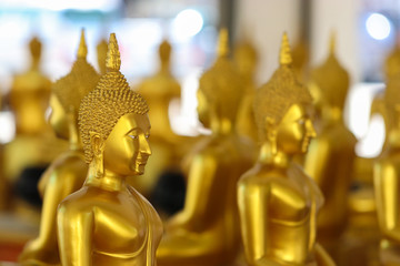 Buddha statue used as amulets of Buddhism religion in Thailand. Golden Yellow glittering background blurred.