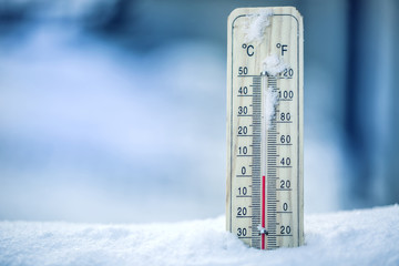 Thermometer on snow shows low temperatures - zero. Low temperatures in degrees Celsius and...