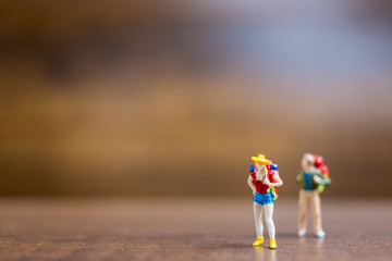 Miniature people travelers standing on wooden background , Travel concept