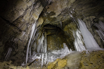 Underground abandoned ore mine shaft tunnel gallery with ice stalactites stalagmites