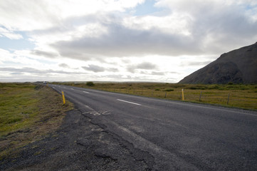 Road in a typical Icelandic landscape, a wild nature of rocks and shrubs, rivers and lakes.