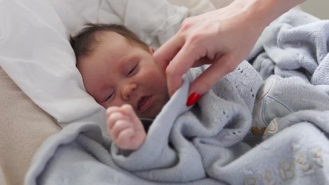 Mother's hand tenderly stroking head of a newborn baby