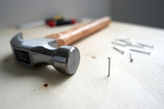 Nails, screws, and a hammer on home improvement construction site