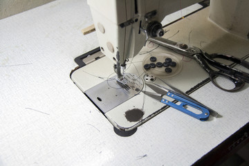 Sewing accessories on the Sewing machine, Includes forceps, Scissors, Scissors Clippers and buttons. it is a garment job for clothes and fashion.