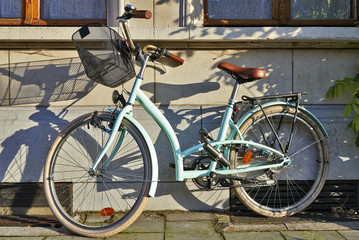 Fototapeta na wymiar Green vintage woman bike attached at wall