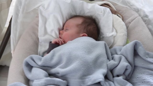 Cute newborn baby sleeping in swinging cradle