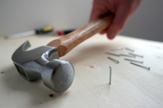 A man picking up a hammer with nails and screws on home improvement construction site