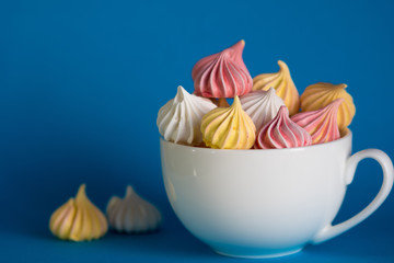 Dessert with meringue, a lot of colorful meringues in the tea Cup