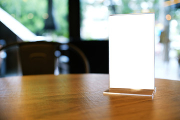 Mock up Menu frame standing on wood table in Bar restaurant cafe. space for text