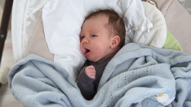 Cute sleepy newborn baby yawning in crib
