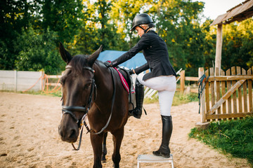 Female jockey and brown stallion, horseback riding