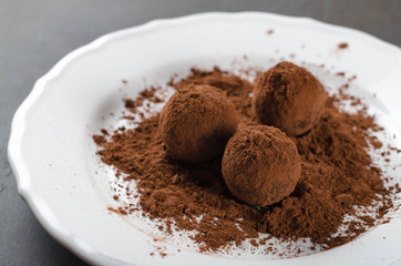 Homemade truffle candies on a white plate, cocoa. Selective focus