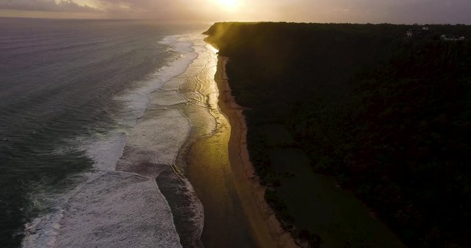 Aerial drone footage of ocean waves breaking before the shore on sunset. Bali, Indonesia