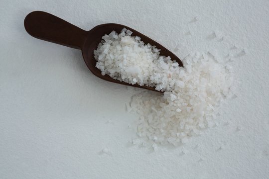 Sea salt scattered out of wooden scoop