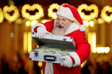 Happy Santa Claus on blurred background. Senior cheerful Santa Claus is opening silver diplomat...