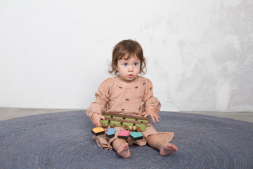 Little happy girl playing with toy on floor. Kindergarten.