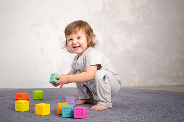 Little happy girl playing with toy on floor. Kindergarten.