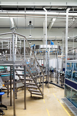 Industrial factory indoors and machinery. Robotic factory line for processing and bottling of pure spring water into canisters and bottles