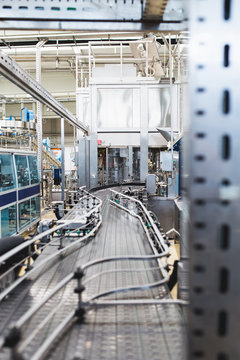 Industrial factory indoors and machinery. Robotic factory line for processing and bottling of pure spring water into canisters and bottles