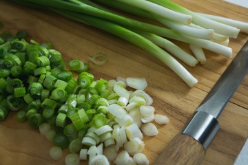 Chopped scallions with knife on chopping board