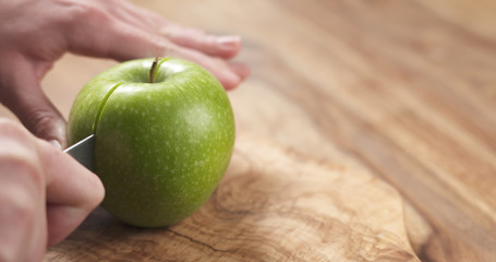young female hands cut green apple into halves