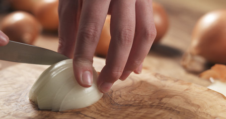 Obraz na płótnie Canvas young female hands slicing white onion