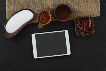 Various spices with digital tablet on black background