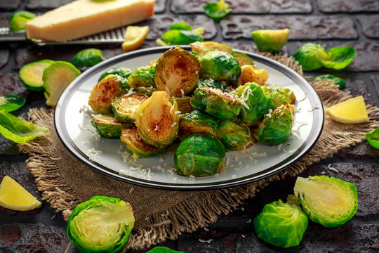 Homemade Roasted Brussel Sprouts with Parmesan cheese, lemon, Salt, Pepper on a old stone rustic table.