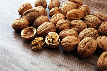 Walnut kernels and whole walnuts on brown wooden table.