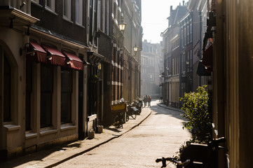 People walk along a narrow Dutch street early in the morning.