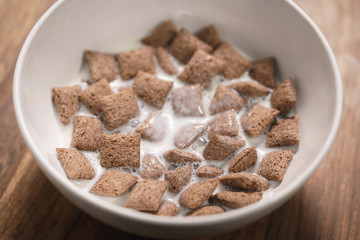 poured with milk chcolate cereal pillow in white bowl on table