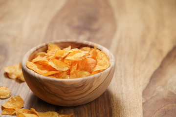 potato chips with paprika in wood bowl on table