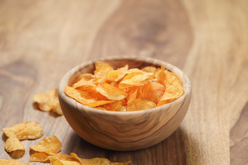 potato chips with paprika in wood bowl on table