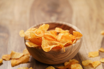 potato chips with paprika in wood bowl on table