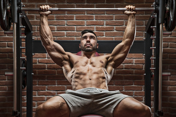 Bodybuilder workout for chest with brick wall on the background.