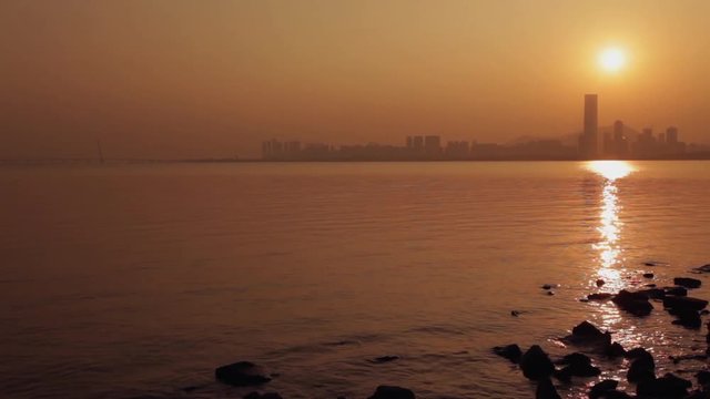 Shenzhen - China, sunset over Nanshan district; skyscraper silhouettes reflecting in water; steadicam footage; 