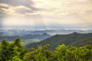 Naklejka premium Dramatic clouds with mountain,tree,fog and sun ray in the early morning.Natural forest concept.