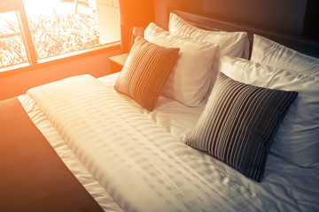 Bed maid-up with clean white pillows and bed sheets in beauty room. Close-up. Lens flair in...