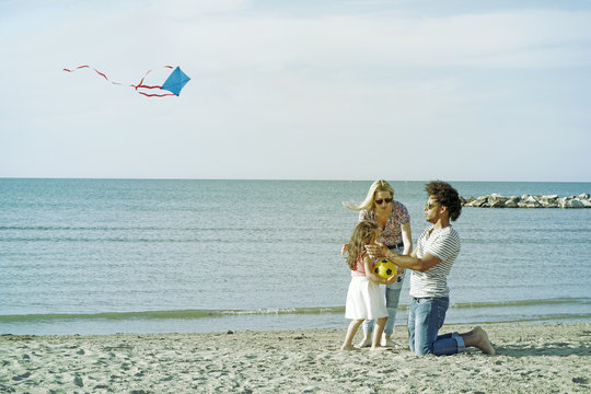 Mixed Race Family Enjoying Day Out On Beach. Exotic Husband And Wife With Child On Holiday Beach  Destination.