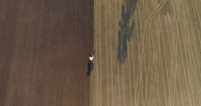 Aerial shot of tractor plowing field. Farmer cultivating arable land for seeding. Top view of soil plowing.