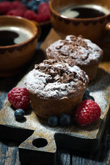 chocolate muffins and fresh berries on wooden board, vertical