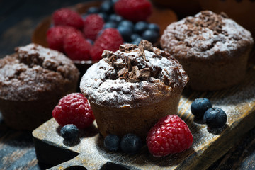 chocolate muffins and fresh berries on wooden board