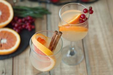 Lemonade with grapefruit, cinamon sticks and red currant served in wine glasses on wooden table