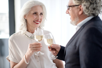 Glad senior woman and man clinking glasses of alcohol beverage