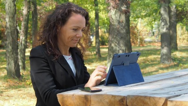 Working in nature. Business woman working on a tablet in the park.