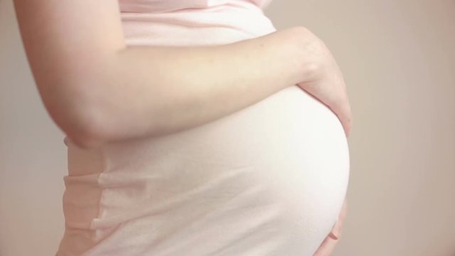 Pregnant woman touching her belly with hands
