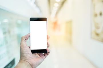 hand use smartphone with background of blur office corridor