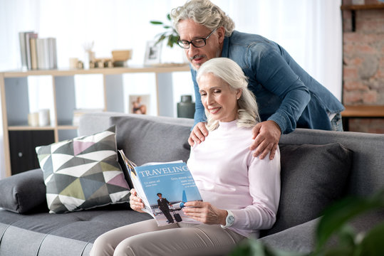 Happy senior man and woman entertaining with journal at home