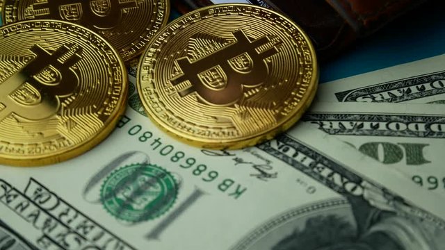 Gold Bitcoin BTC coins rotating with brown wallet and bills of 100 dollars. Worldwide virtual internet cryptocurrency Digital coin money and digital payment system on bitcoin farm in cyberspace