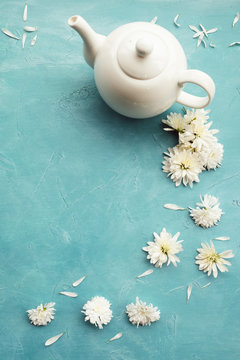 Hot healthy organic herbal tea. White teapot on blue background